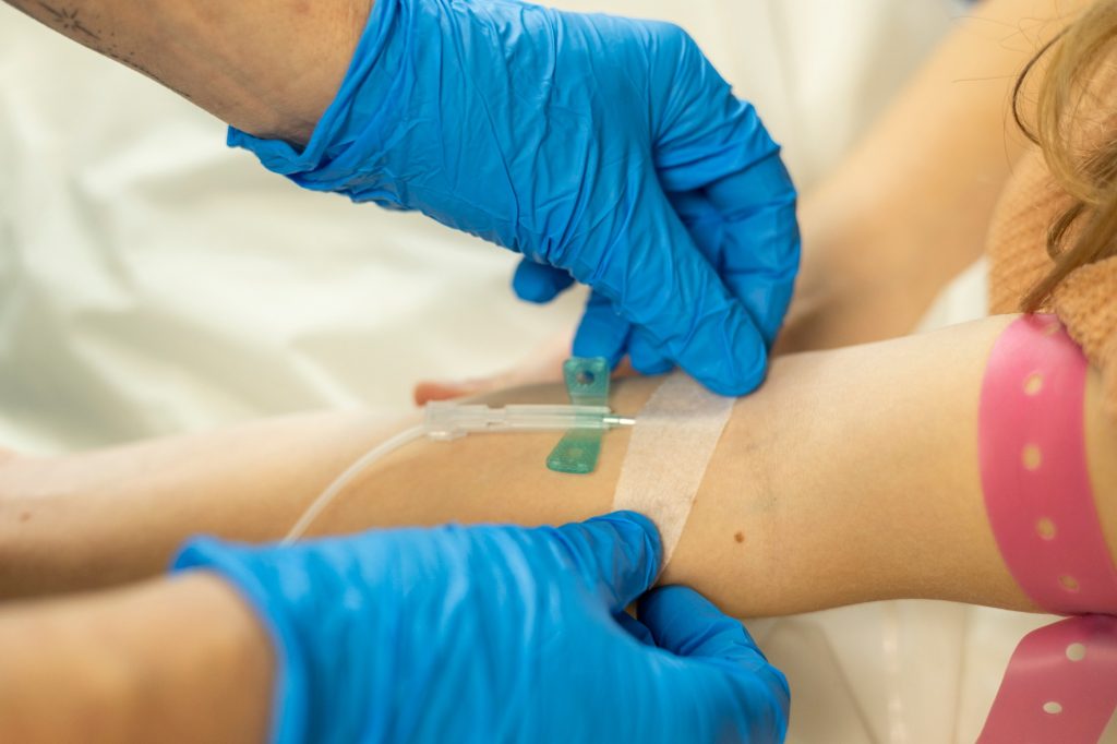 Medical professional inserting an IV catheter into a patient's arm.
